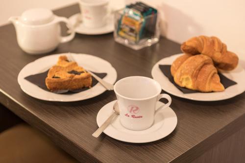 Una mesa con platos de pasteles y una taza de café. en La Ruota, en Morbegno