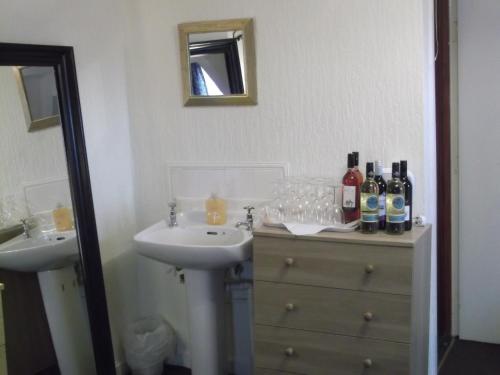 uma casa de banho com 2 lavatórios e uma cómoda com garrafas e copos em Durham house hotel em Gateshead