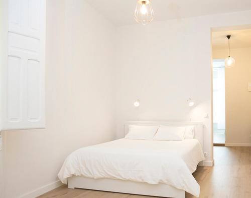 a white bedroom with a white bed and a chandelier at MEZZANINe GREEN in Madrid