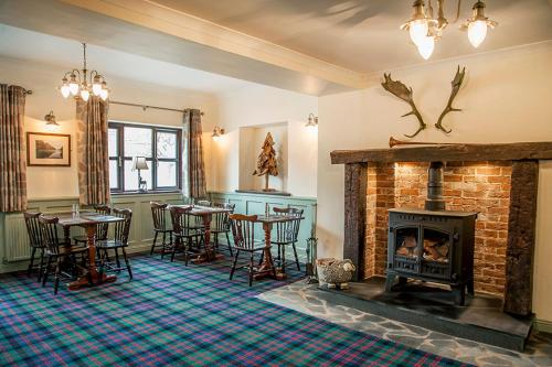 a living room with a fireplace and tables and chairs at The Fir Tree Country Hotel in Fir Tree