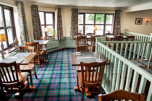 a restaurant with wooden tables and chairs and windows at The Fir Tree Country Hotel in Fir Tree