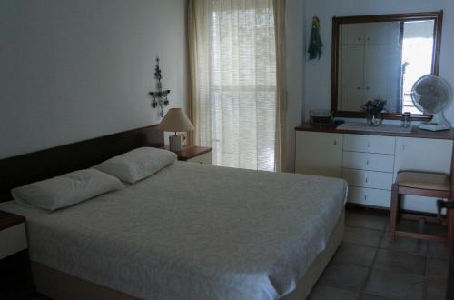 ネア・ポティダイアにあるHoliday Home by the Seaのベッドとドレッサーと鏡のある寝室