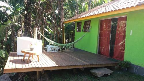a green house with a hammock on a wooden deck at chales azaleia todos in São Bento do Sapucaí