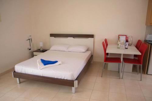 1 dormitorio con 1 cama y 1 mesa con sillas rojas en Peyia Pearl en Peyia