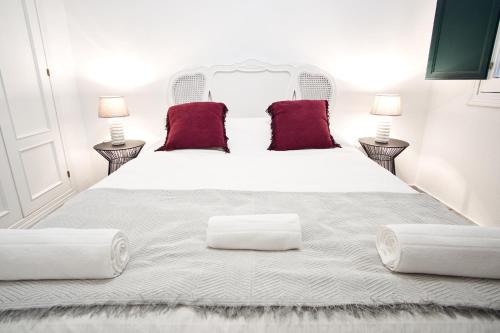 um quarto com uma grande cama branca com almofadas vermelhas em Monsalves Courtyard by Valcambre em Sevilha