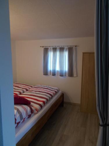 Bett in einem Zimmer mit Fenster in der Unterkunft Ferienhaus am Langen See II in Heidesee