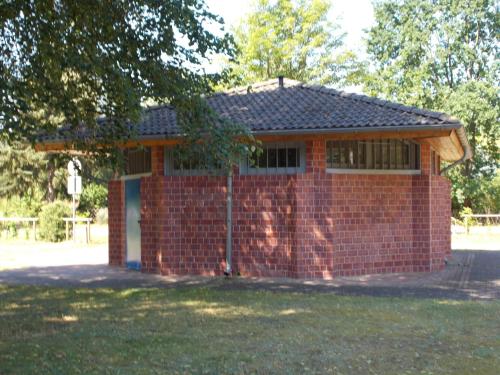 a small red brick building with a door at Ferienhaus am Langen See II in Heidesee