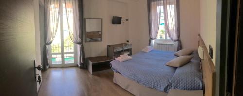 a bedroom with a blue bed and two windows at Hotel Marinella in Celle Ligure