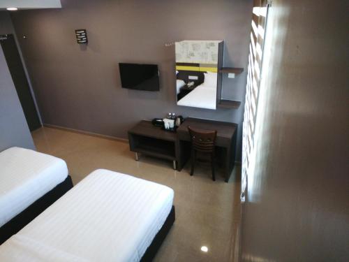 a room with two beds and a table and a desk at Kampar Boutique Hotel in Kampar