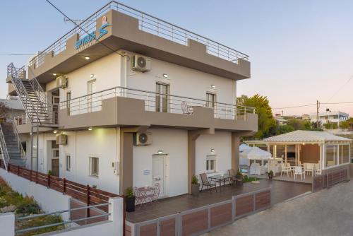 a white building with a balcony and a patio at Spyros Apartments with Pool in Kalamaki