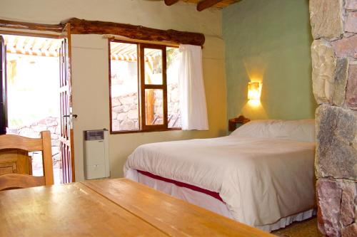 a bedroom with a bed and a table and windows at Posada Don Juan in Tilcara