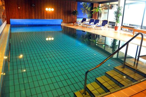 een zwembad met trappen en stoelen in een gebouw bij Hotel Niedersfeld-Winterberg in Winterberg