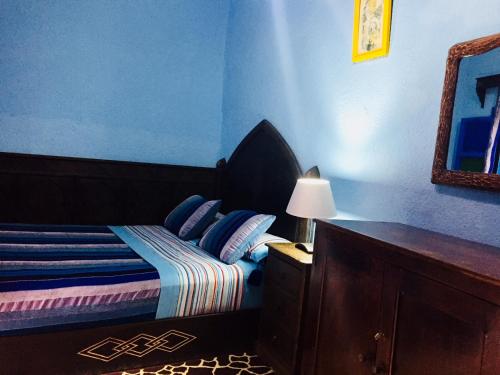 a bedroom with a bed with blue walls and a mirror at Dar Antonio in Chefchaouene