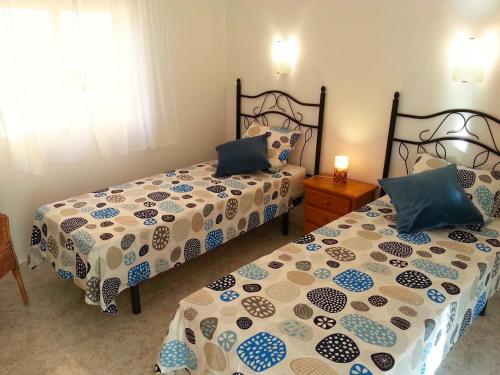um quarto com 2 camas com lençóis azuis e brancos em Apartment Vistamar 3 em Cumbre del Sol