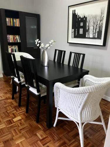 a black dining room table with chairs and a vase with flowers at Lauramer Apartamento Bakio in Bakio