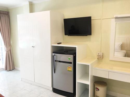 a kitchen with a refrigerator and a tv on the wall at Thai Orchid Guest House in Jomtien Beach