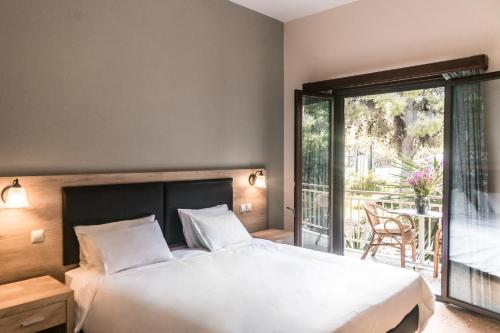 a bedroom with a large bed and a balcony at The Delfini Hotel in Agia Marina Aegina