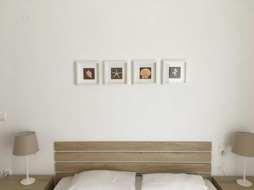 a bedroom with a white wall with four pictures on it at Alegria Kefalonia in Katelios