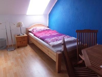 a small bed in a room with a blue wall at Gästehaus Weinviertel - Niederösterreich in Siebenhirten