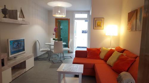 a living room with a orange couch and a table at Apartamentos Dalia in Vecindario