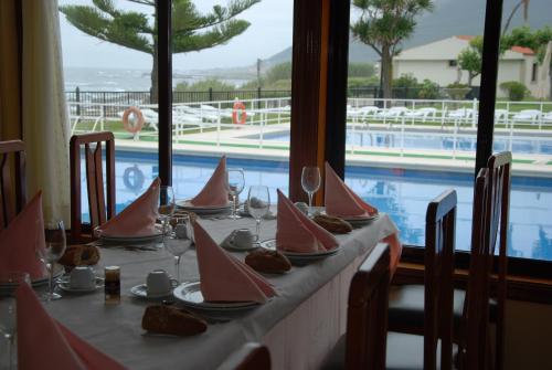 a table with plates of food and a swimming pool at Hotel Restaurante Glasgow in Villadesuso