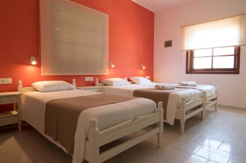 two beds in a room with red walls at Niki Rooms in Palaiochóra