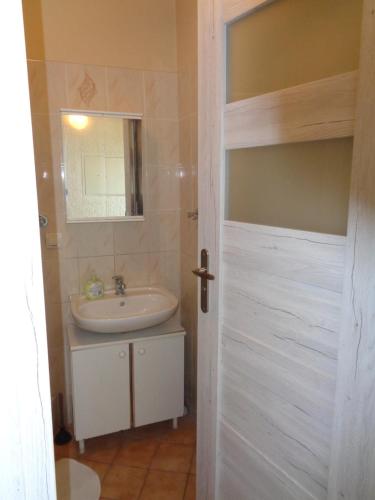 een badkamer met een wastafel, een spiegel en een deur bij Uroczy Domek Z Ogrodem I Tarasem in Myślenice