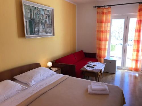 een slaapkamer met een bed en een rode bank bij Summer rooms Baška in Baška