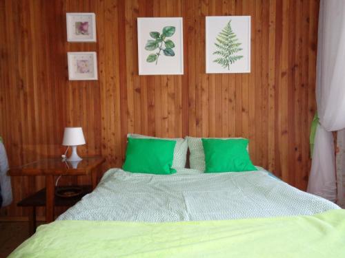 a bedroom with a bed with green sheets and pictures on the wall at Uroczy Domek Z Ogrodem I Tarasem in Myślenice