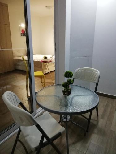 a glass table and two white chairs in a room at Chicos Studios in Ayia Napa