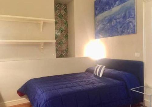 um quarto com uma cama com um cobertor azul e um candeeiro em Loft duca di..... em Catânia