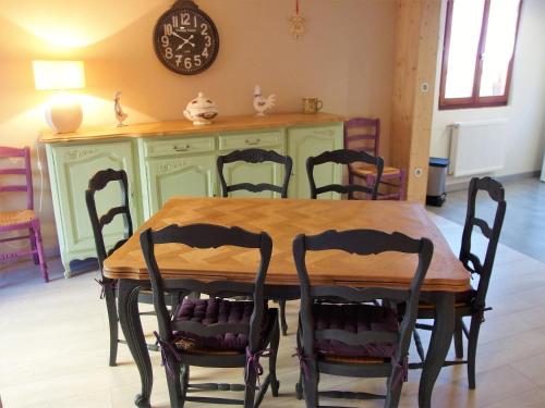 a dining room table with chairs and a clock on the wall at La maison Céline in Bergheim