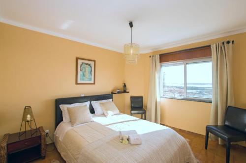 Apartamento Ria Formosa في فوزيتا: غرفة نوم بسرير كبير ونافذة