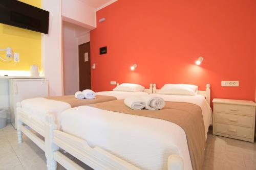 two beds in a room with a red wall at Niki Rooms in Palaiochóra