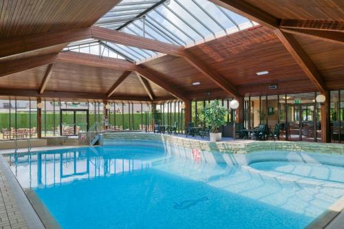 a large swimming pool in a building with a glass ceiling at Airport Inn & Spa Manchester in Wilmslow