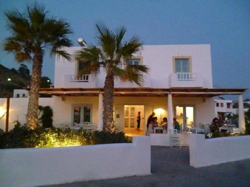 a white house with palm trees in front of it at Oklacà Patmos Beach Rooms in Patmos