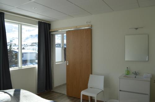 1 dormitorio con puerta, cama y ventana en The Old Post Office Guesthouse, en Grundarfjordur