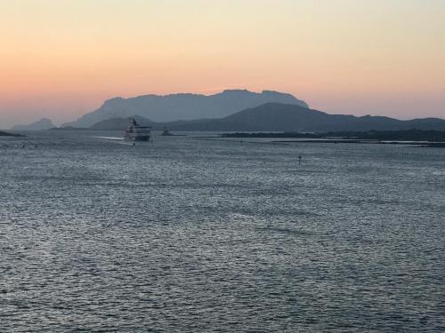 a boat in the water with mountains in the background at Bados Mare in Olbia