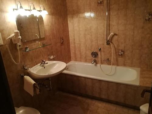 ein Badezimmer mit einer Badewanne, einem Waschbecken und einem Spiegel in der Unterkunft Residence Terentis in Terenten