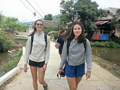 two girls walking down a path next to a river at Ngan Ha Homestay in Ha Giang