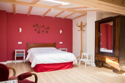 1 dormitorio con cama blanca y pared roja en Casa Rural el Cedro en Abejar