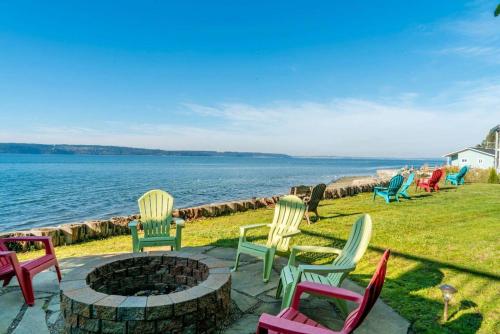 a group of chairs around a fire pit next to the water at Camano Island Inn in Camano