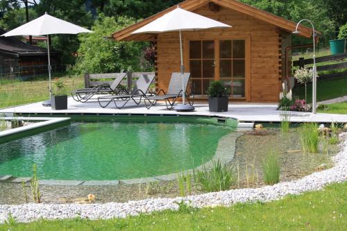a pool with chairs and umbrellas in a backyard at Ferienhaus Alpinissimo in Oberammergau