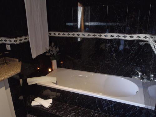 uma banheira na casa de banho com azulejos pretos em sand and sea na Póvoa do Varzim