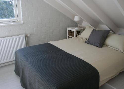 a bedroom with a bed in a attic with a window at Bungalow Schotvanger in Egmond aan den Hoef