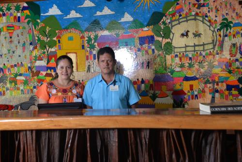 a man and a woman standing at a table with a laptop at Hotel Aura del Mar in Zihuatanejo