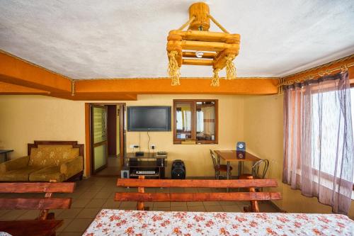 a living room with wooden benches and a television at Piatra Rancii in Ranca