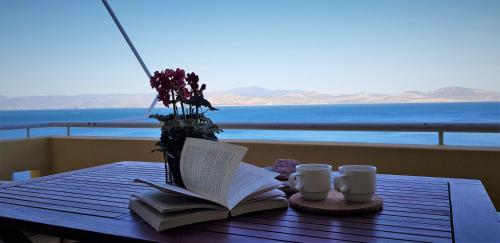 a table with a book and a vase of flowers and coffee cups at Kiveri Gems Houses in Kivérion