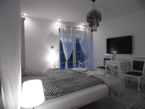 a white bedroom with a bed and a window at Villa Śnieżka in Kowary
