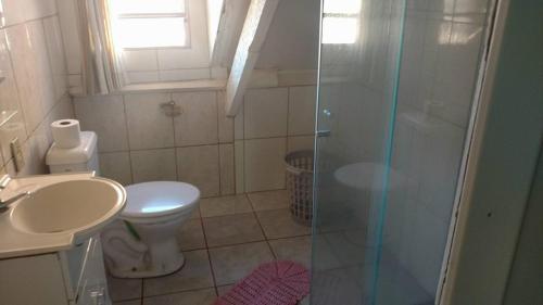 a bathroom with a toilet and a glass shower at Pensão da Celia in Ribeirão Preto